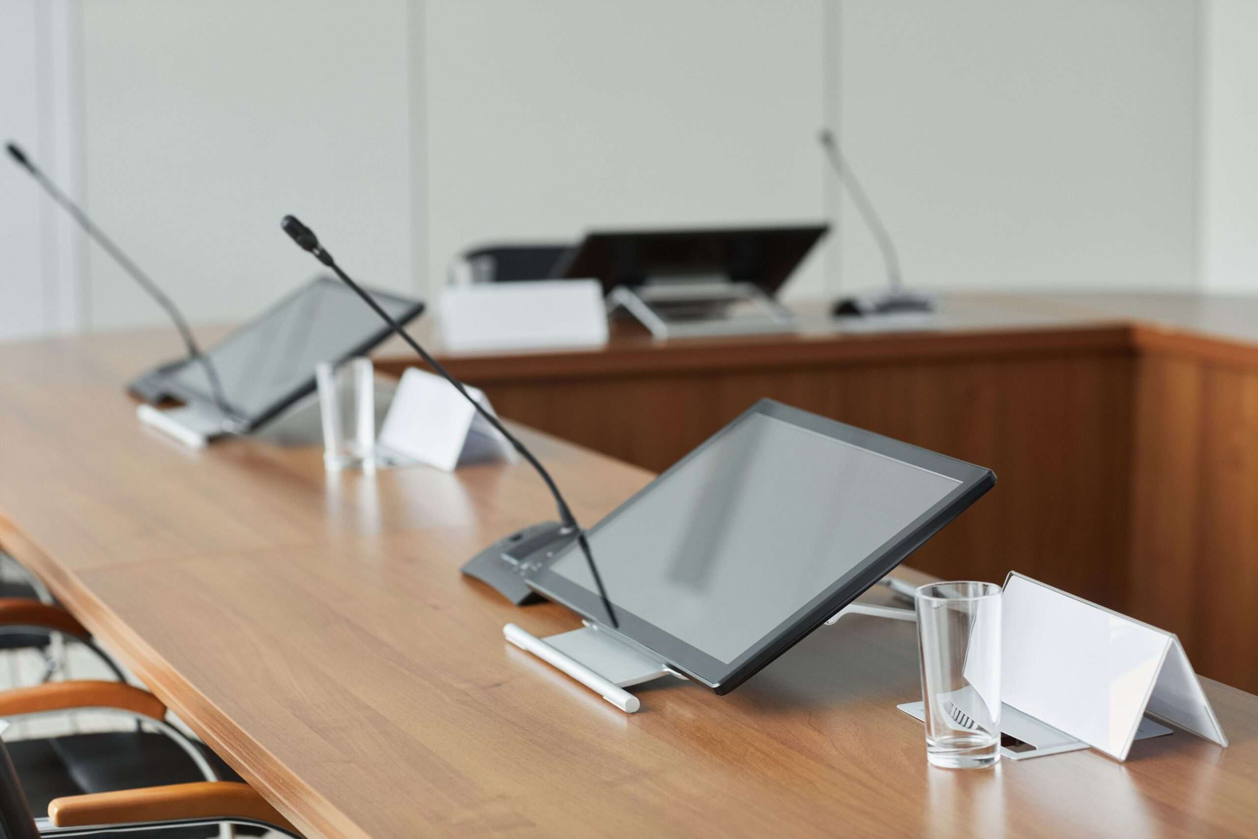 Microphones and monitors on a wooden meeting-room table