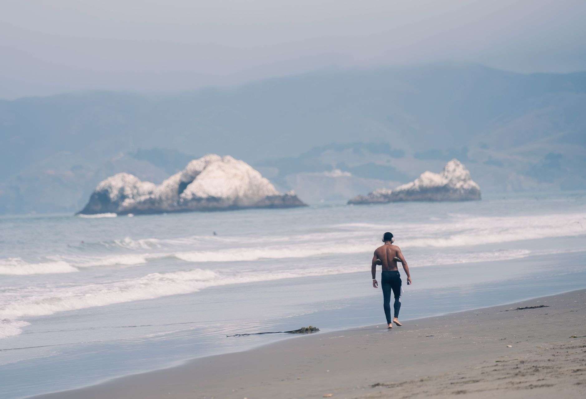 A man walking alone along a quiet beach in the morning