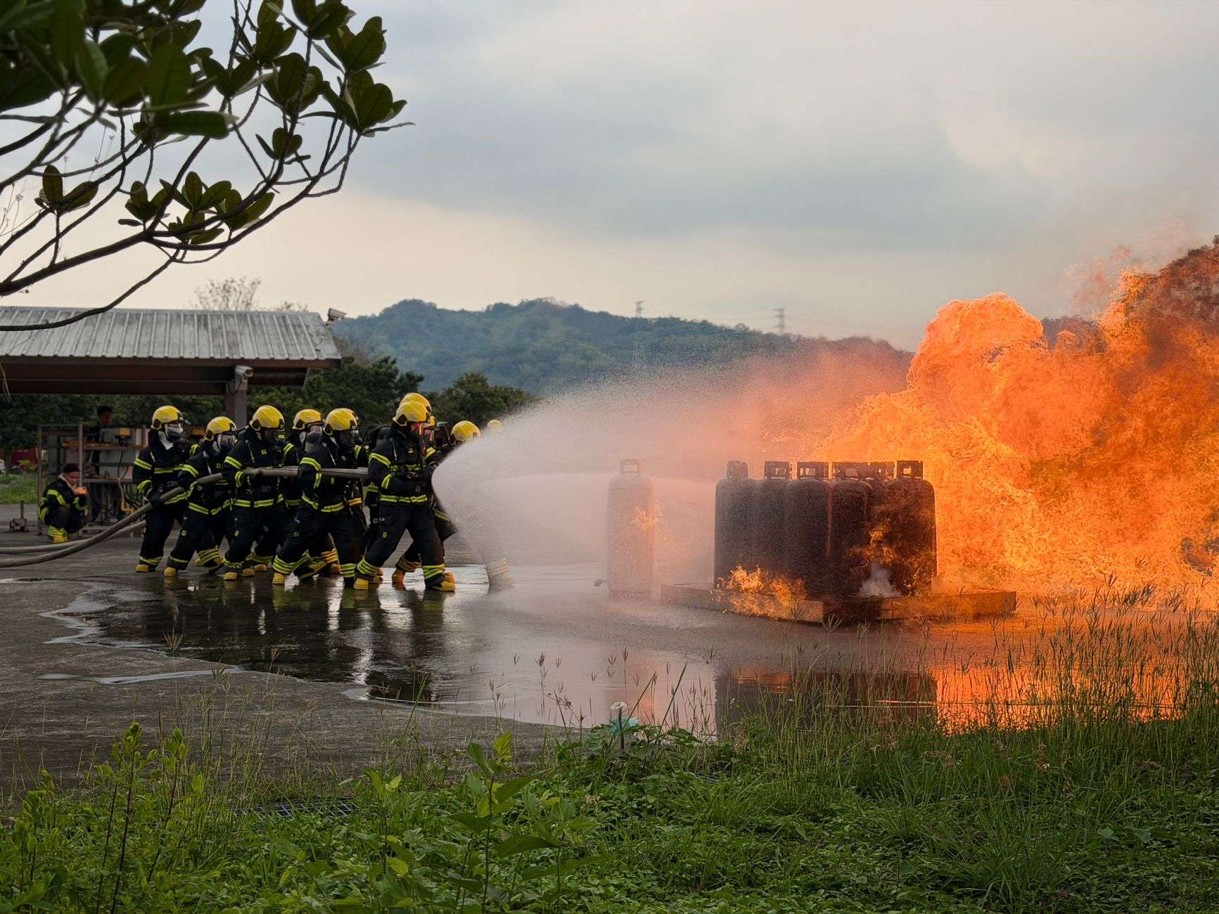 Firefighters in full protective gear working through a training exercise with a hose line