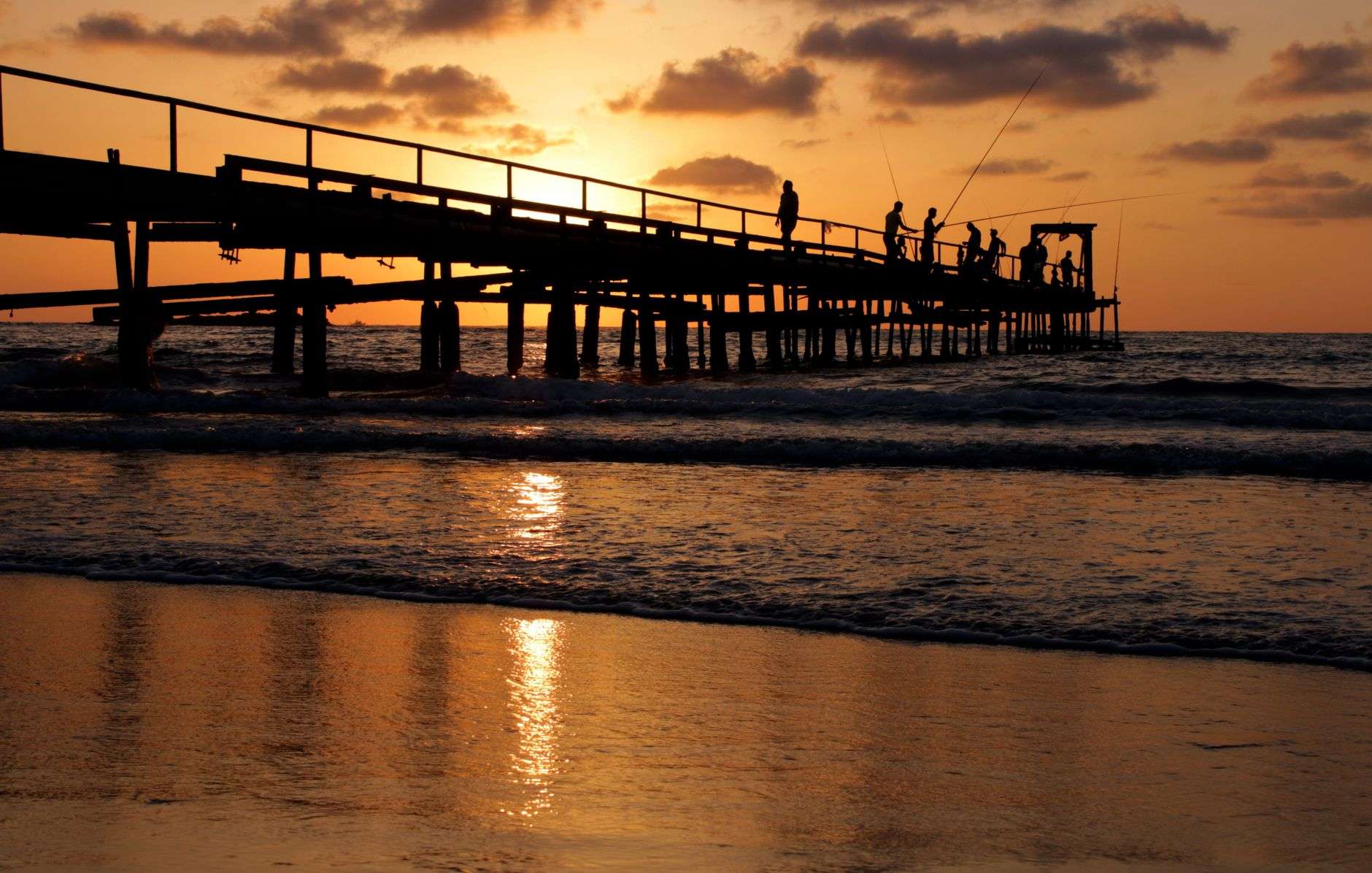 A fishing pier extending out over Gulf waters at sunrise
