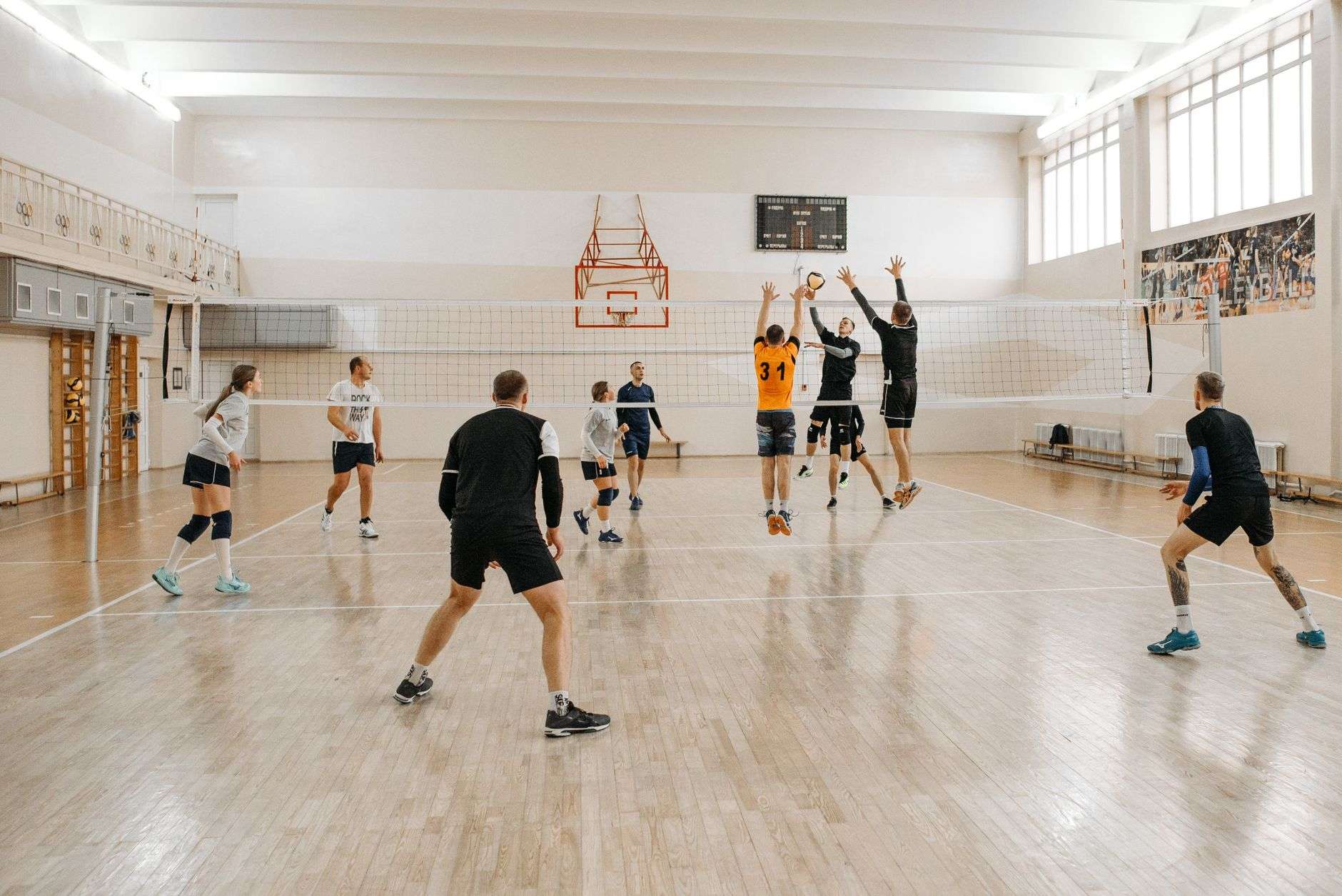 A volleyball net in a high school gymnasium, illustrating a varsity volleyball match