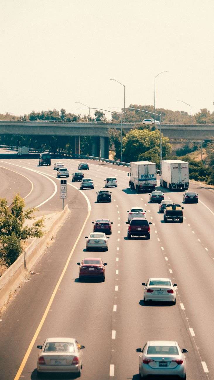 Multiple lanes of highway traffic with cars and trucks under a clear sky