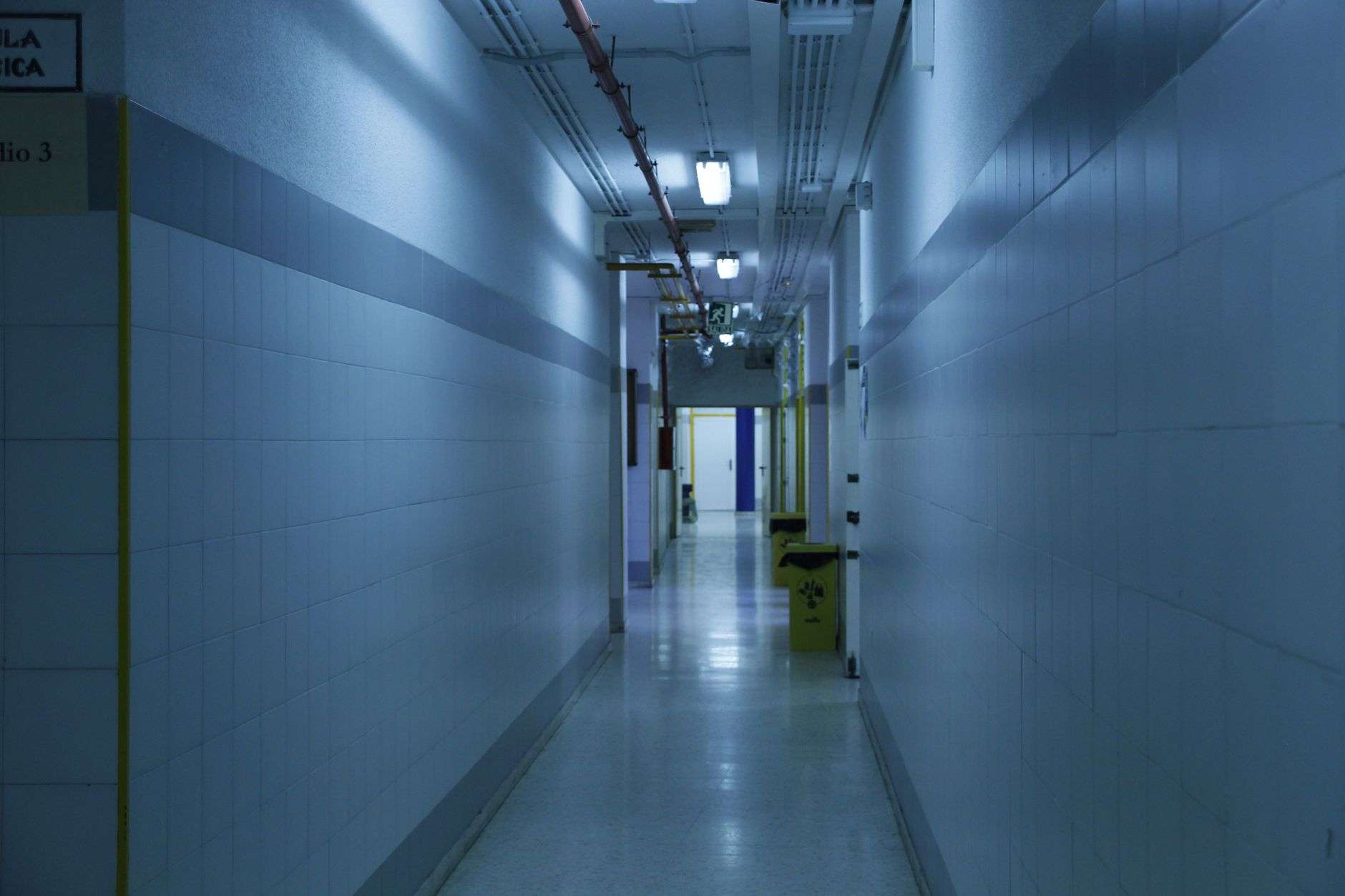 A quiet, brightly lit hospital corridor with doorways along both sides