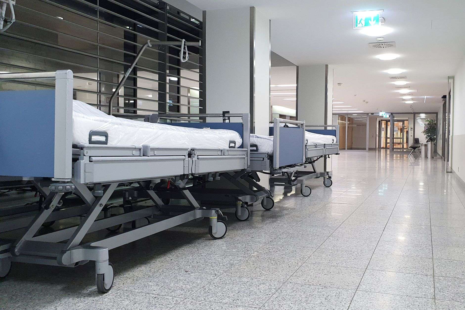 A bright hospital hallway lined with empty hospital beds