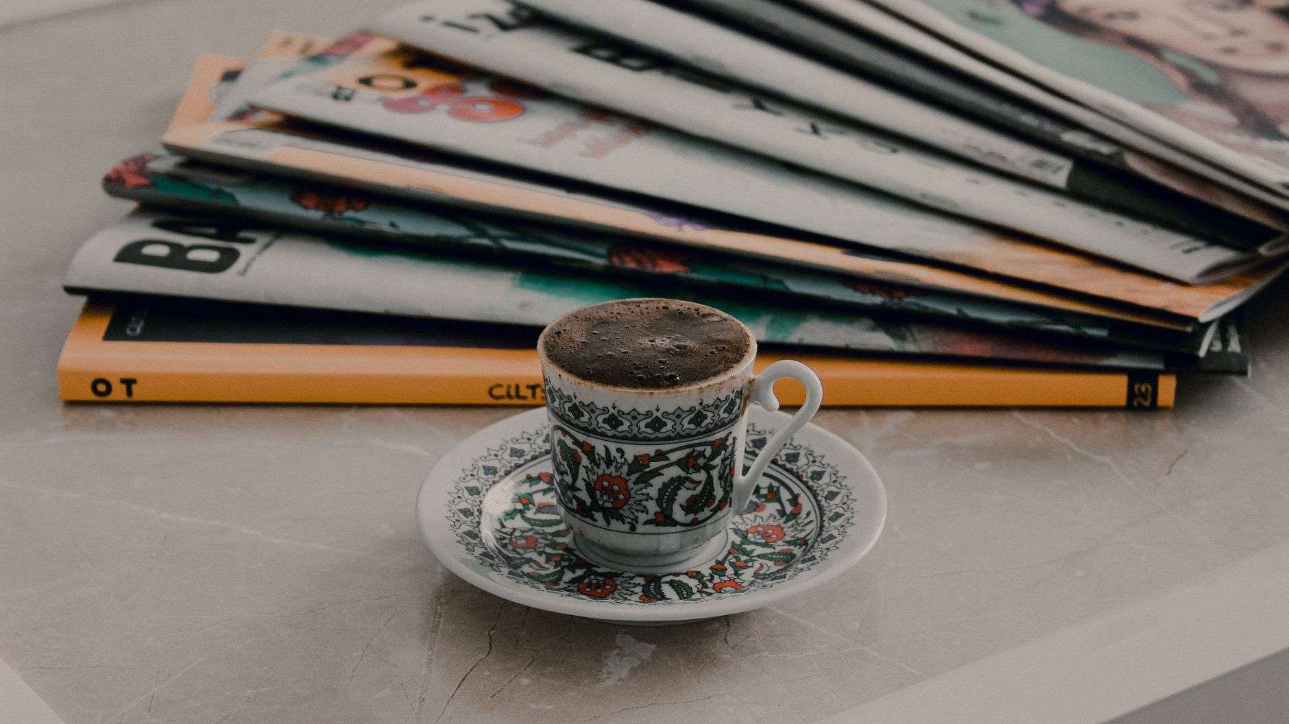 A printed magazine resting on a restaurant table beside a drink
