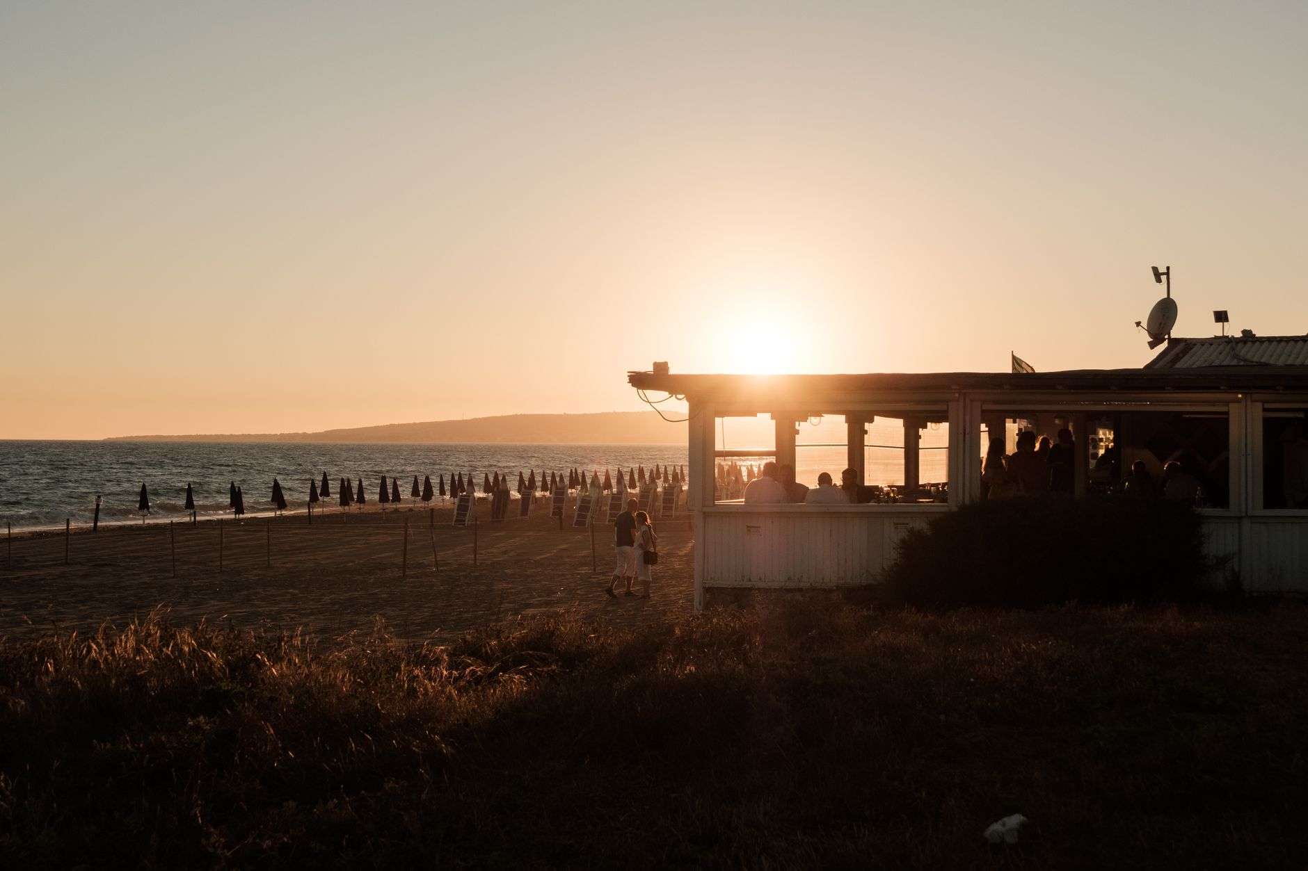 Band performing on an outdoor stage near the water at sunset