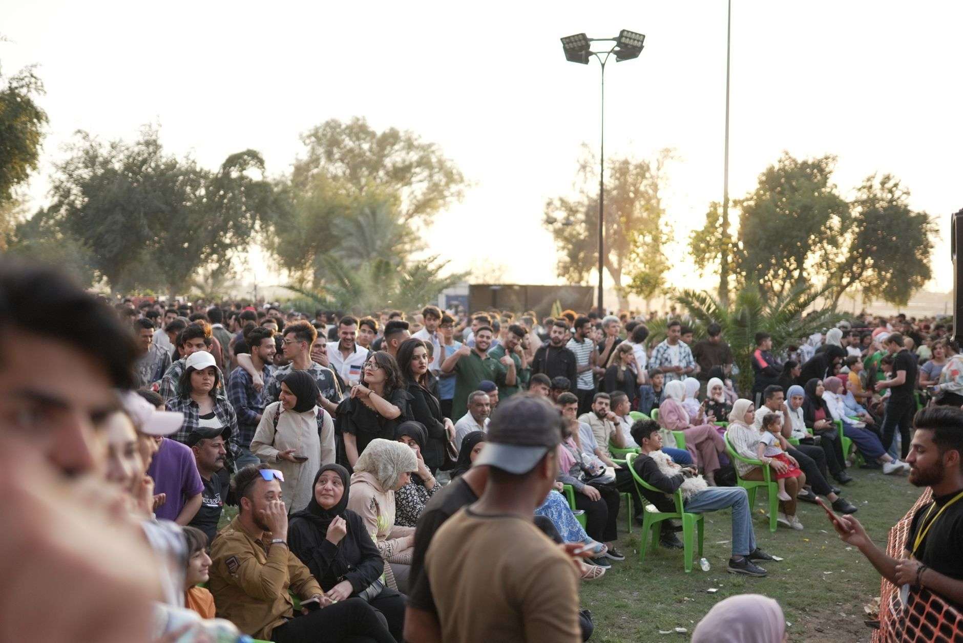 Concertgoers on a lawn watching a band perform on an outdoor stage