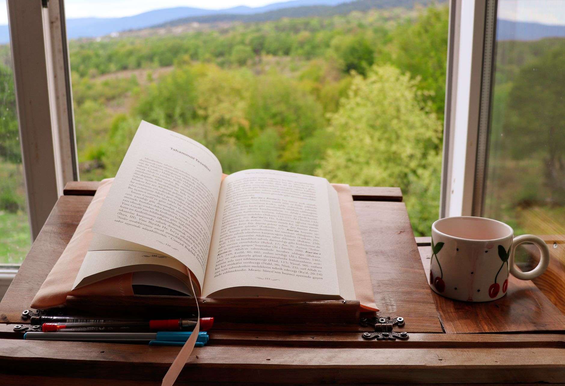 An open hardcover book resting on a table near a window