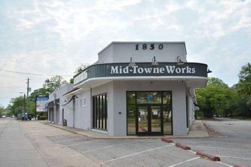 The white single-story exterior of the Mid-Towne Works building at 1850 Airport Boulevard, with glass entry doors and a painted sign