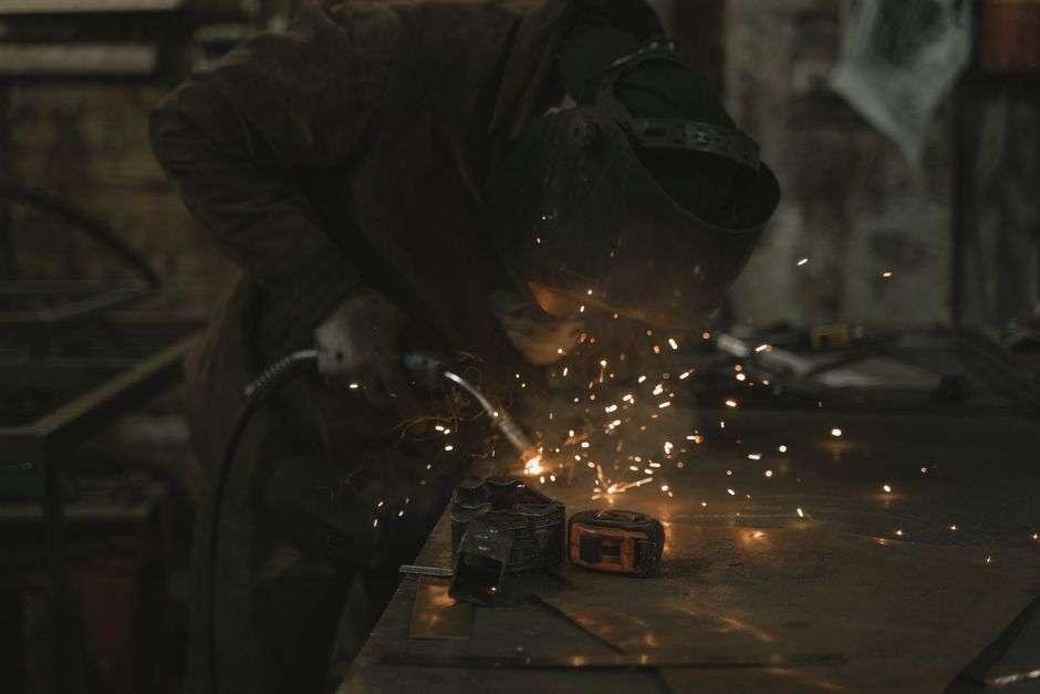 A metal fabricator working with welding sparks in an industrial metal workshop