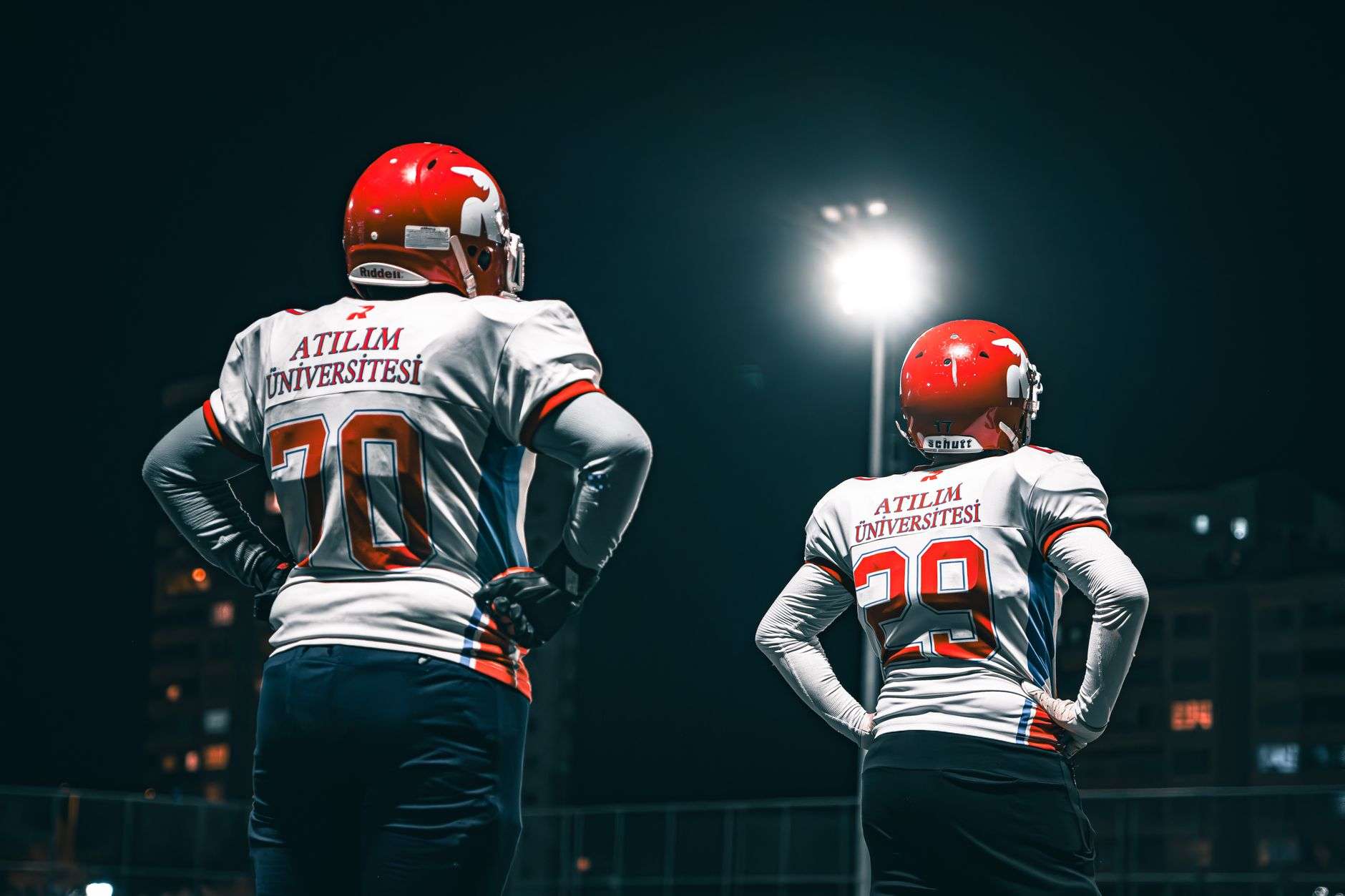College football players lined up at the line of scrimmage under stadium lights at night