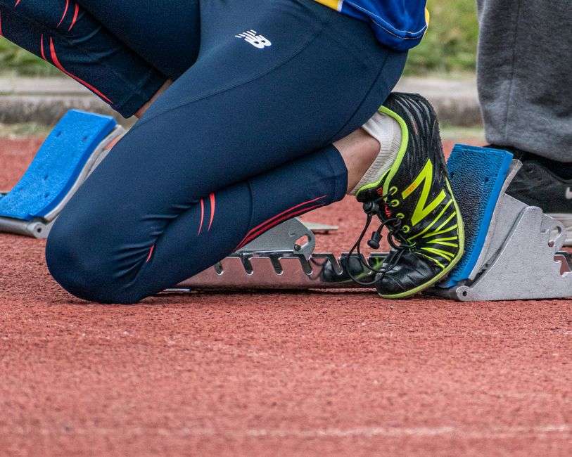 A sprinter crouched in the starting blocks on a running track