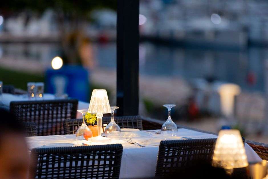 An upscale waterfront restaurant dining room with a view of the bay at sunset