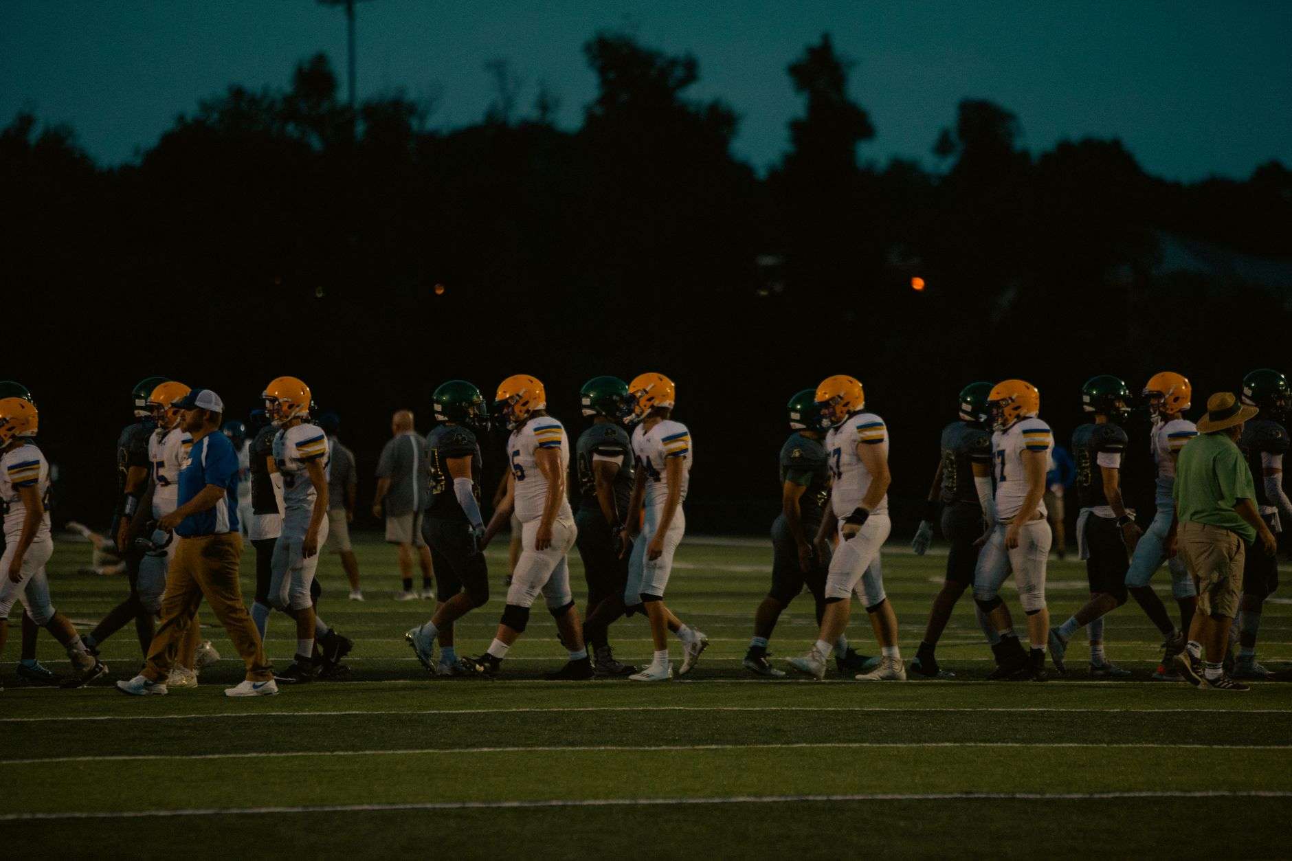 Football players on the sideline during a night game