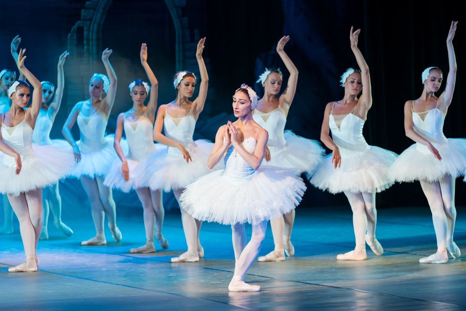 Ballet dancers in costume performing on a lit theater stage
