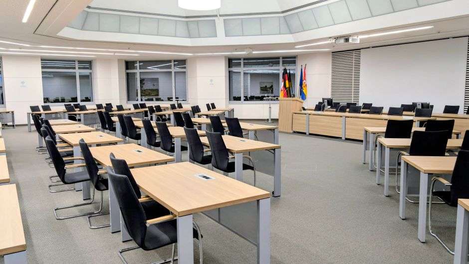 An empty chair at the head of a government meeting table
