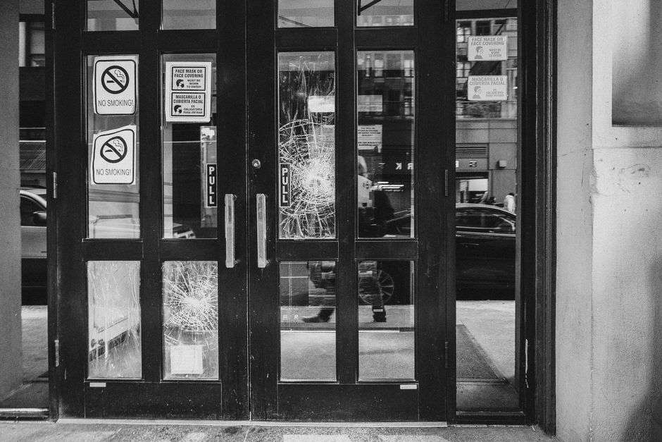 A storefront with a damaged glass door photographed at night