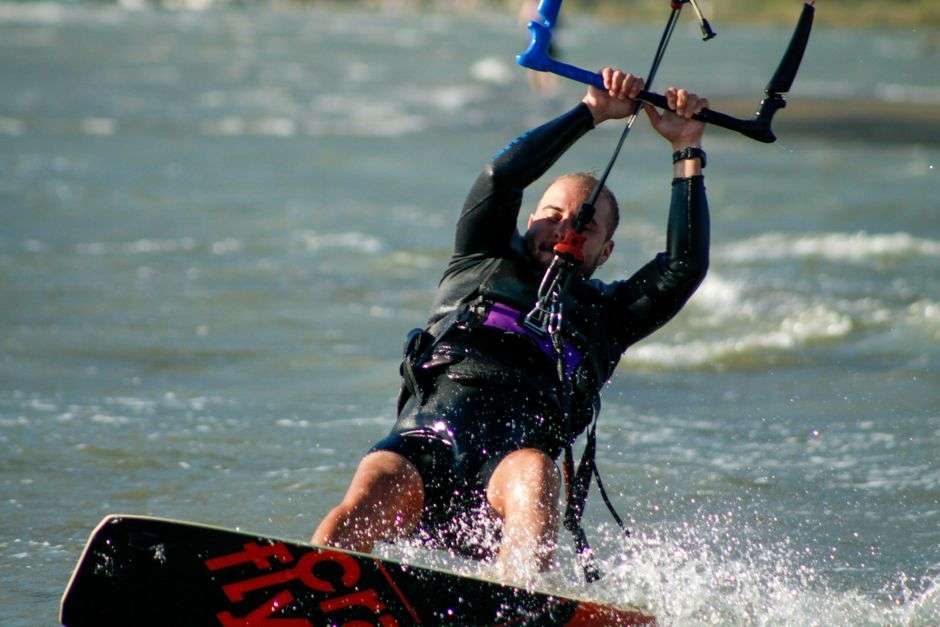 Kitesurfer gliding across the water beneath a large colorful kite