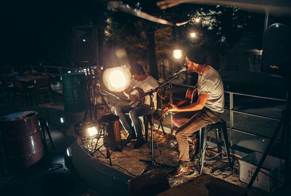 Two musicians playing acoustic guitars on a small stage during a live show