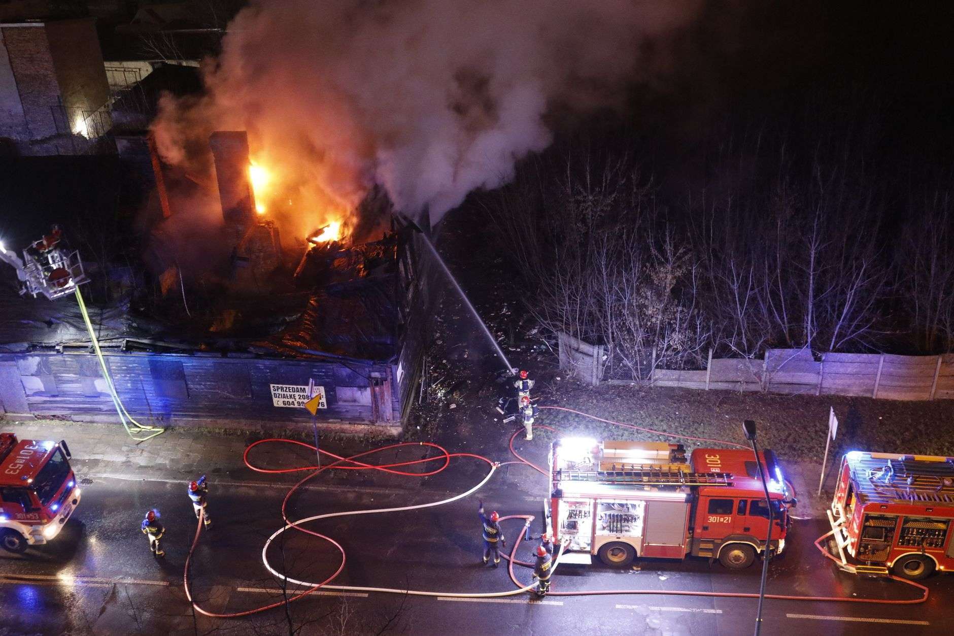 Firefighters directing a hose at a burning residential structure
