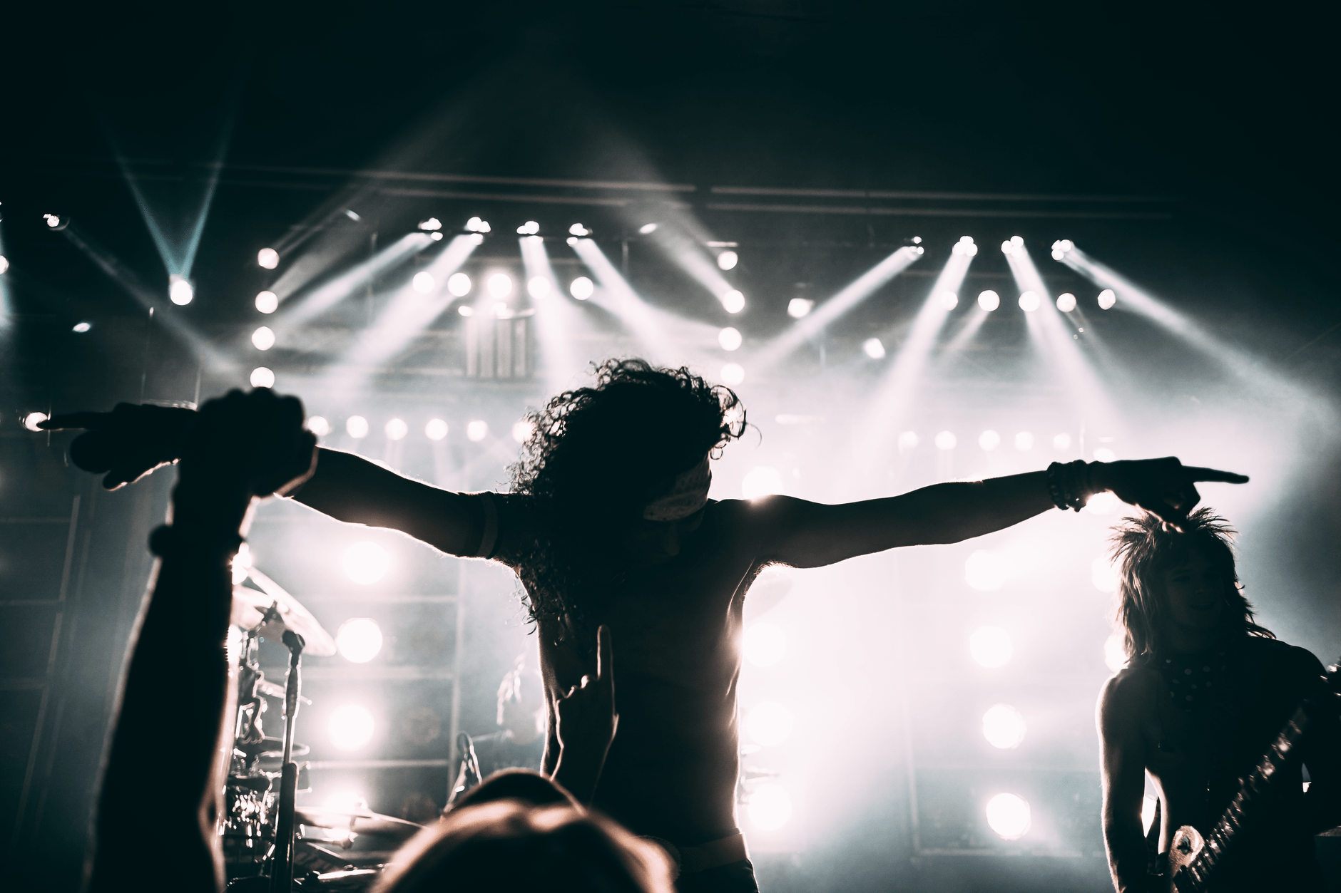 A rock band performing on a small club stage under stage lights