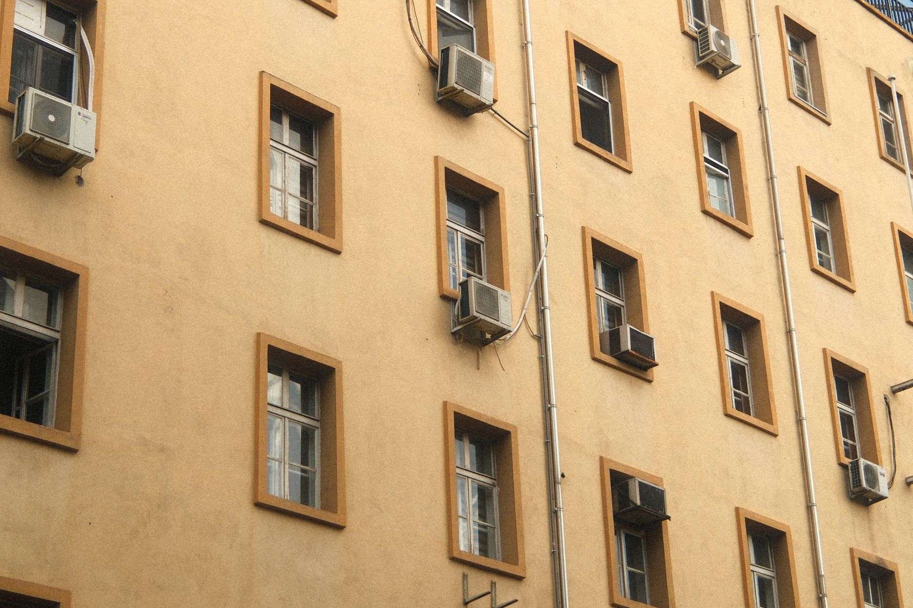 Row of outdoor air conditioning condenser units beside a commercial building