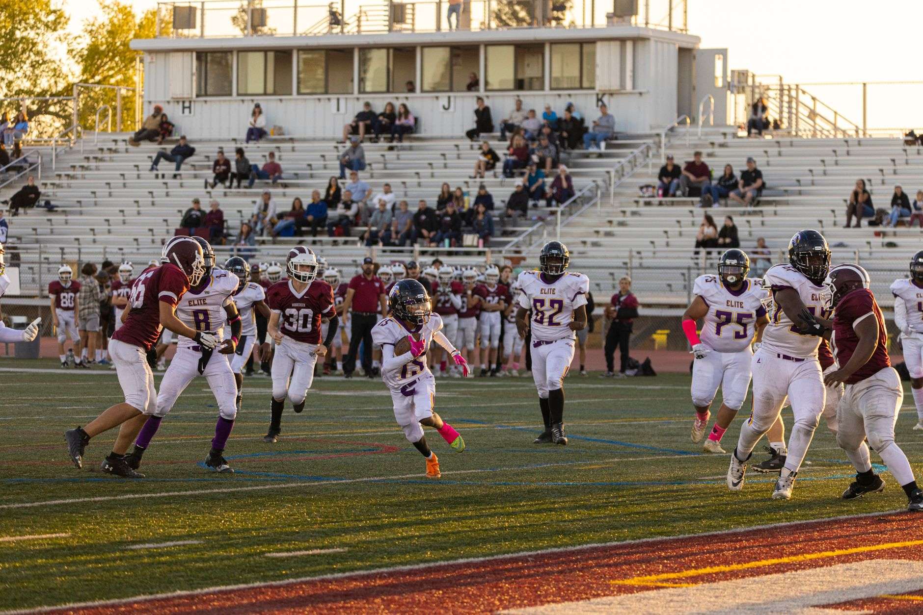 A high school football player running with the ball in the open field