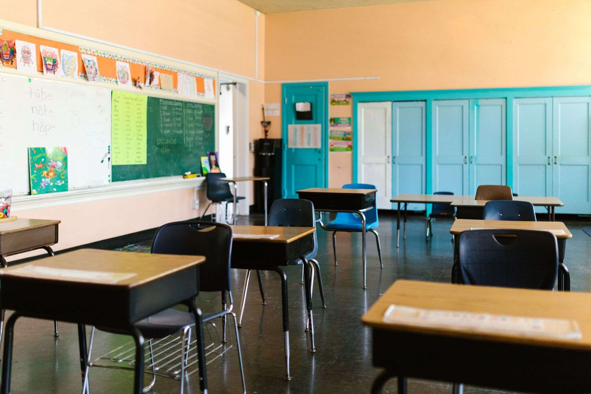 An empty public school classroom with rows of student desks facing a whiteboard