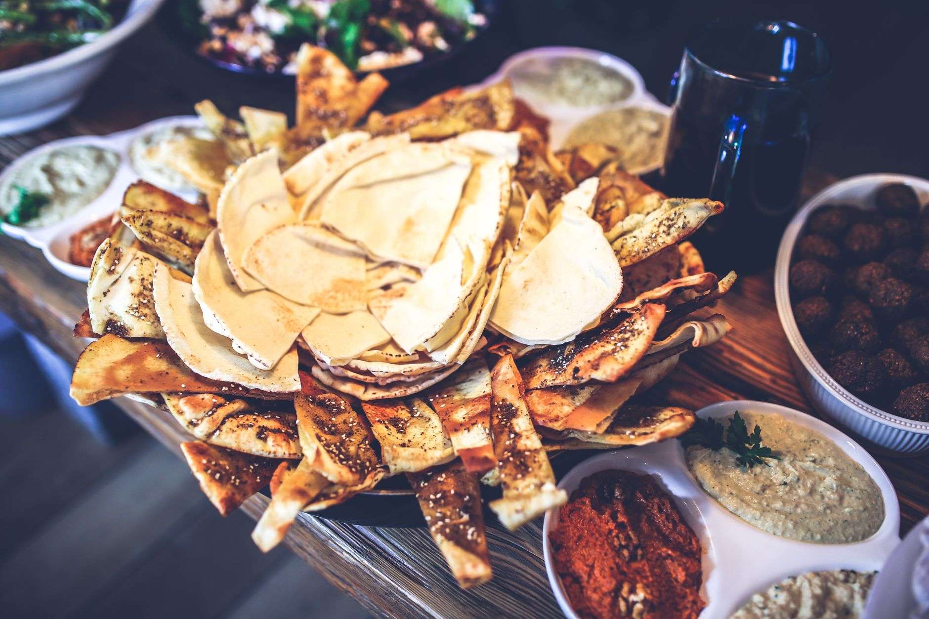 A spread of Mediterranean specialty foods including dips and fresh bread, illustrating a Lebanese food counter