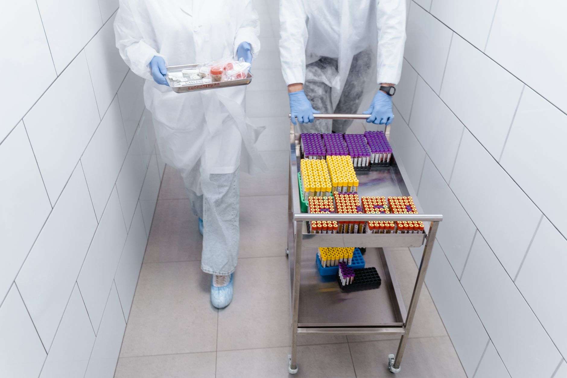A gloved hand collecting a water sample in a sterile bottle at the edge of a bay