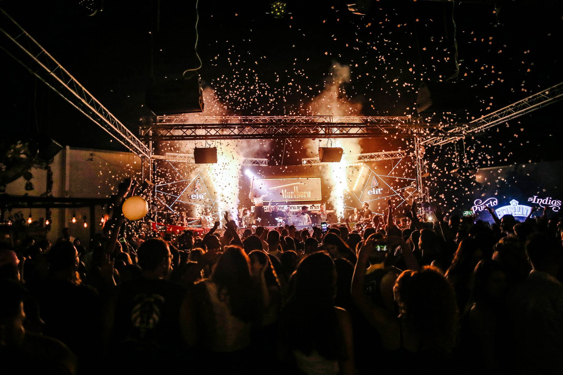 Crowd enjoying a rock band performing on an outdoor stage at dusk
