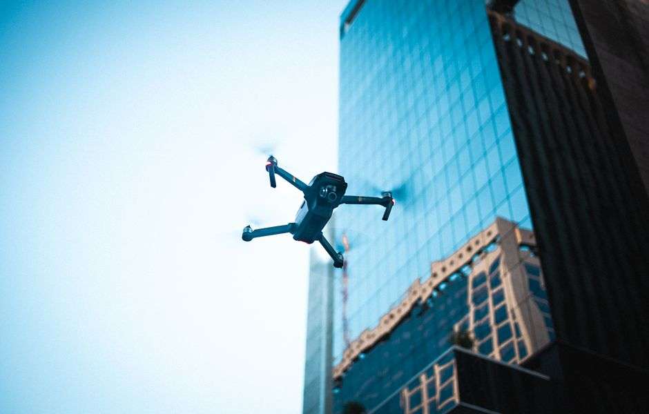 A drone flying above a city with buildings in the background