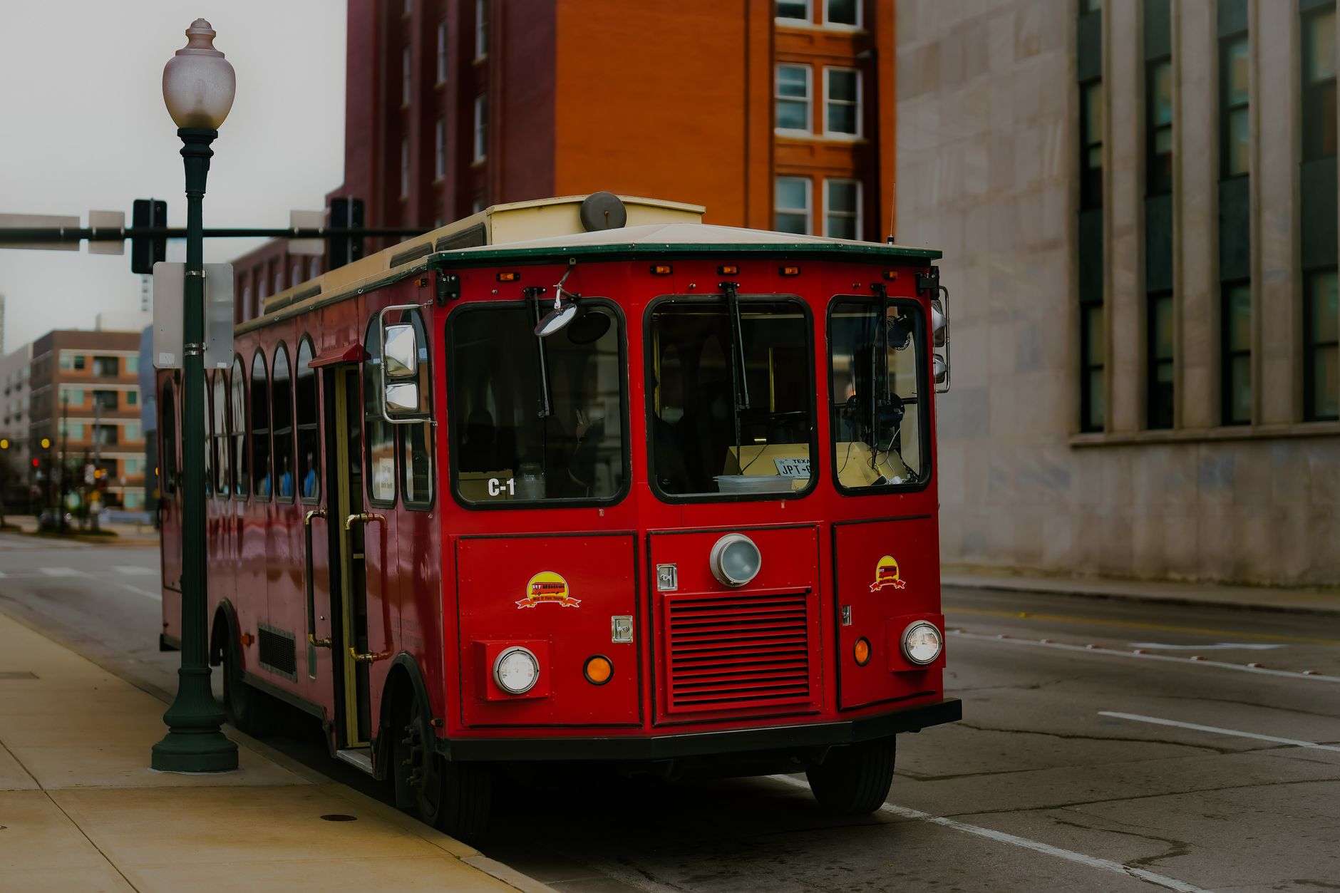 A trolley-style bus with wooden trim traveling along a downtown street