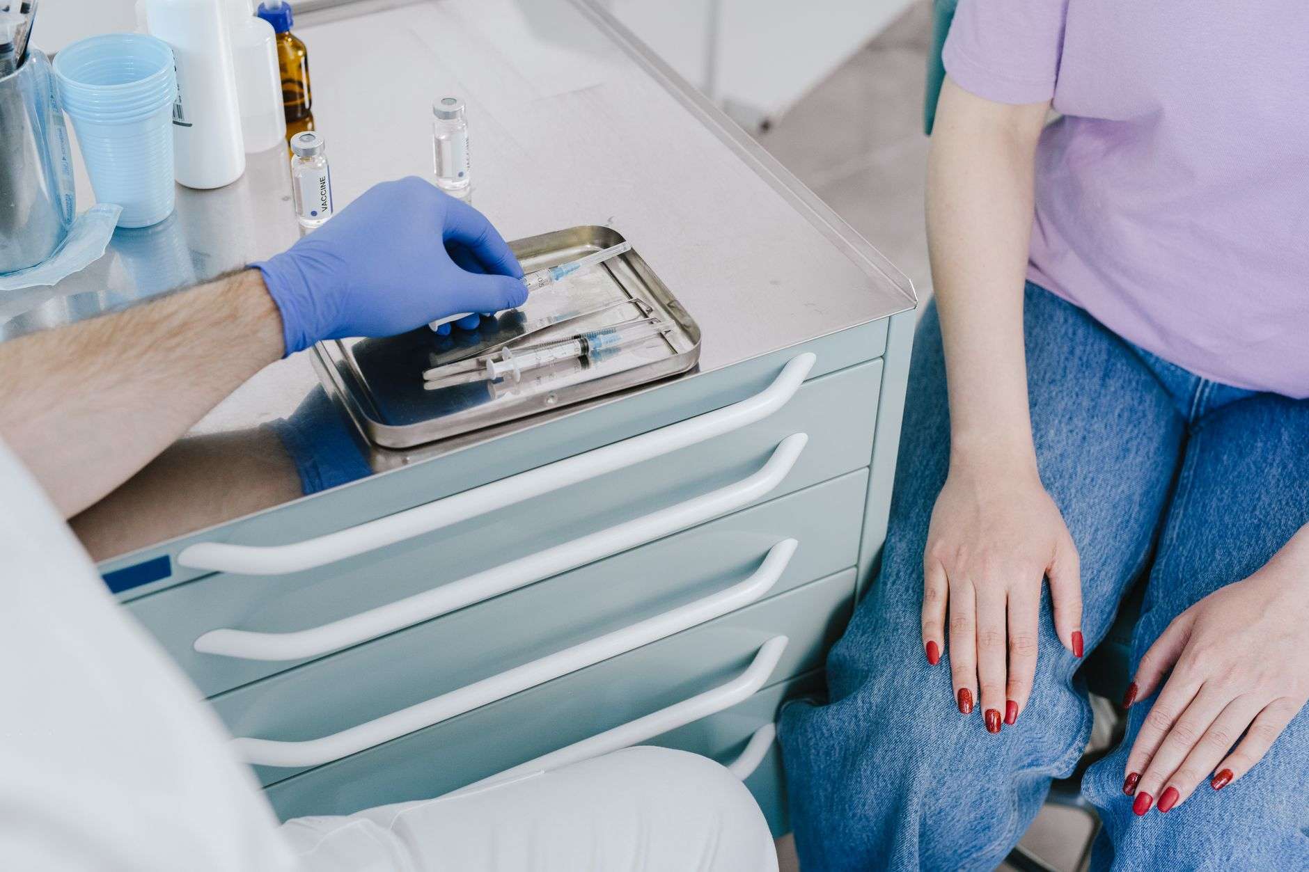A gloved hand drawing seasonal flu vaccine into a syringe at a clinic