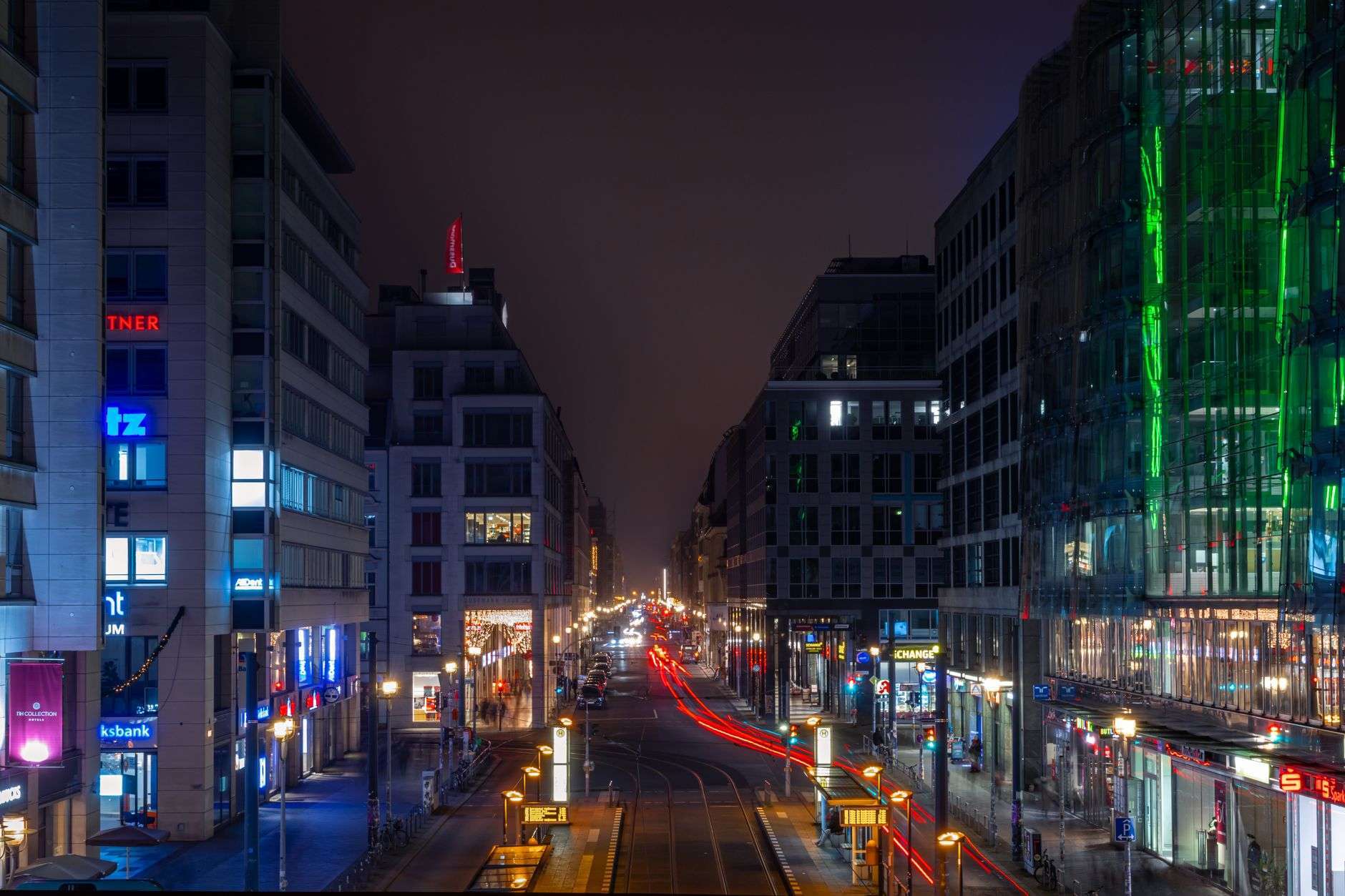 A downtown city street with storefronts lit in the evening