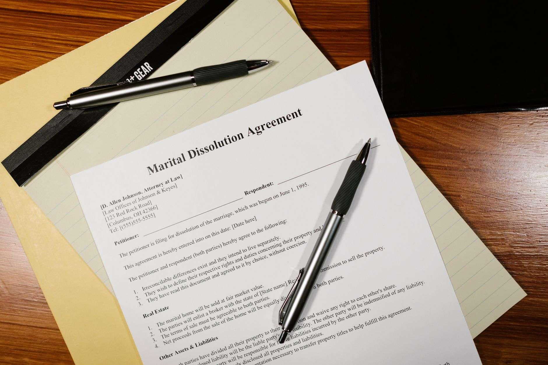 A stack of legal documents and a pen resting on a wooden desk