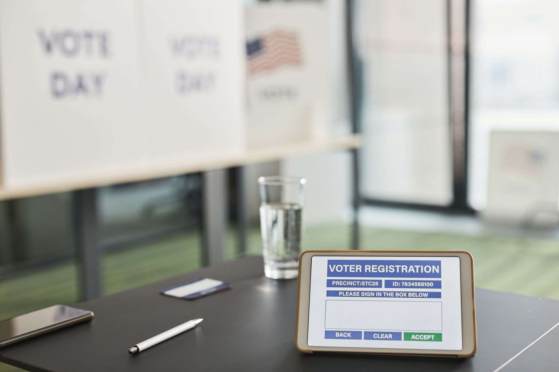 Tablet showing digital voter registration at a voting station with vote signs