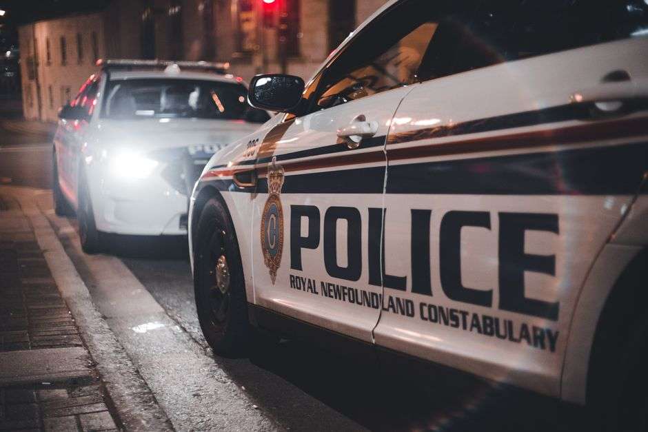A police car with emergency lights activated on a city street at night