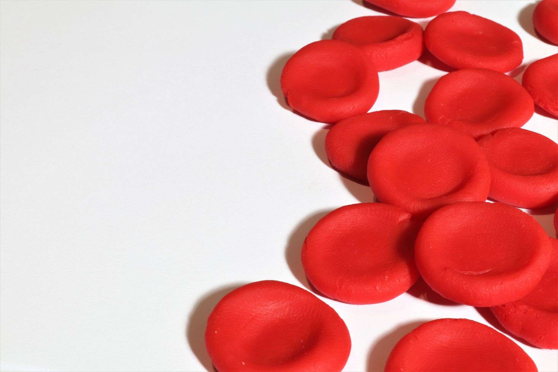 Illustration of red blood cells, including curved sickle-shaped cells, flowing through a blood vessel