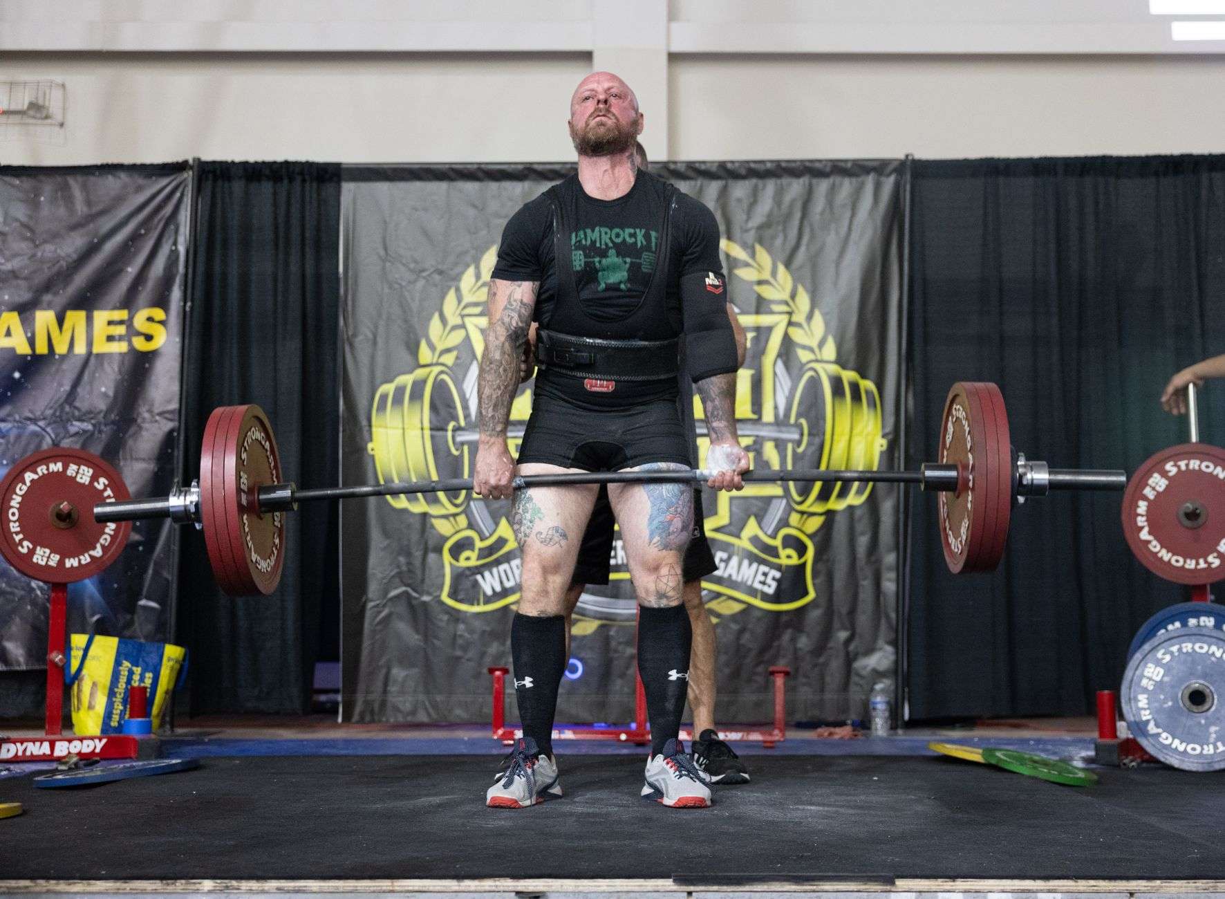 An athlete straining to lift a heavily loaded barbell in a training hall
