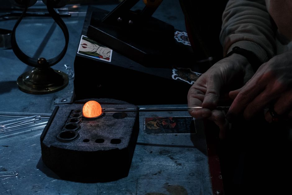 Glassblower shaping a piece of molten glass at a workshop furnace