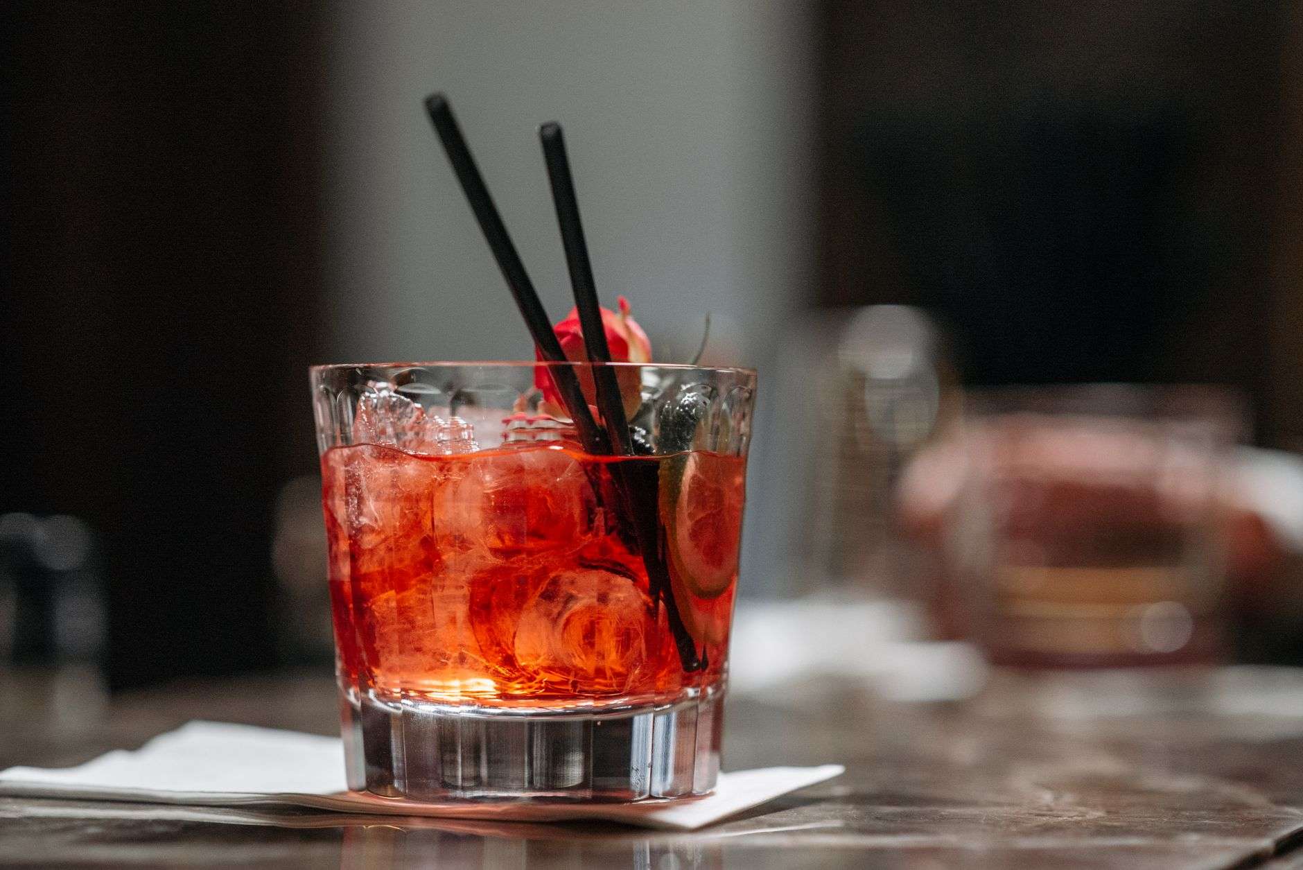 A red Negroni cocktail with an orange peel garnish on a bar counter