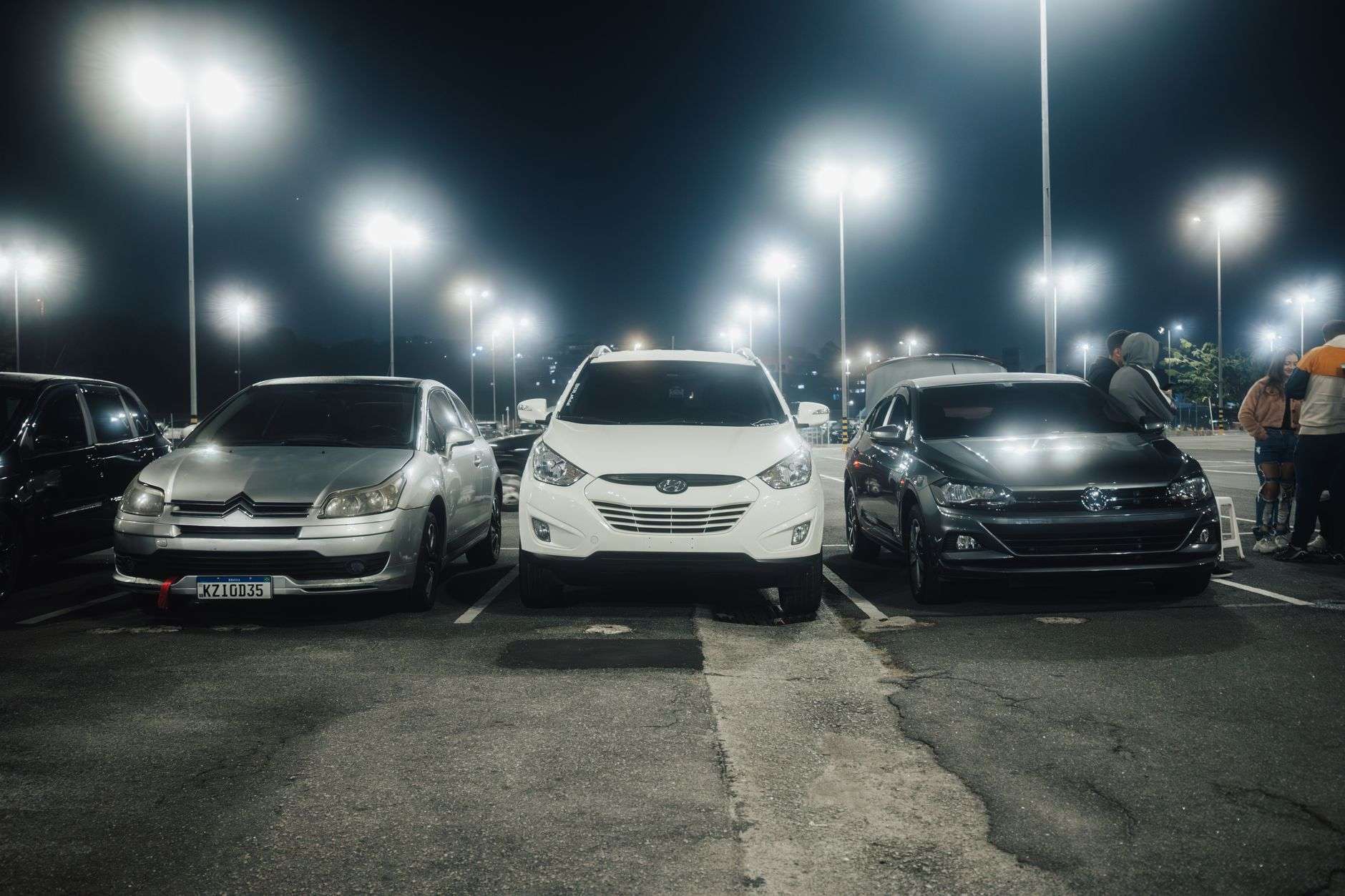Cars parked in an apartment complex parking lot under lights at night