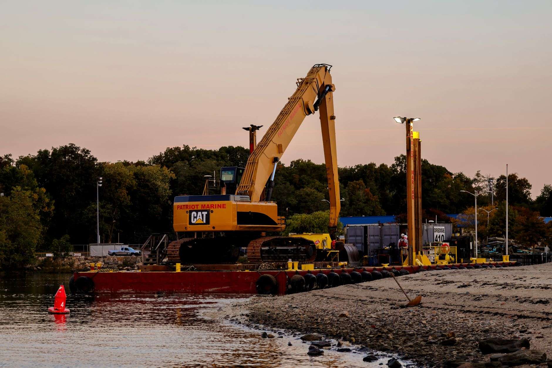 A dredging vessel and pipeline at work in a river channel with wooded banks in the background