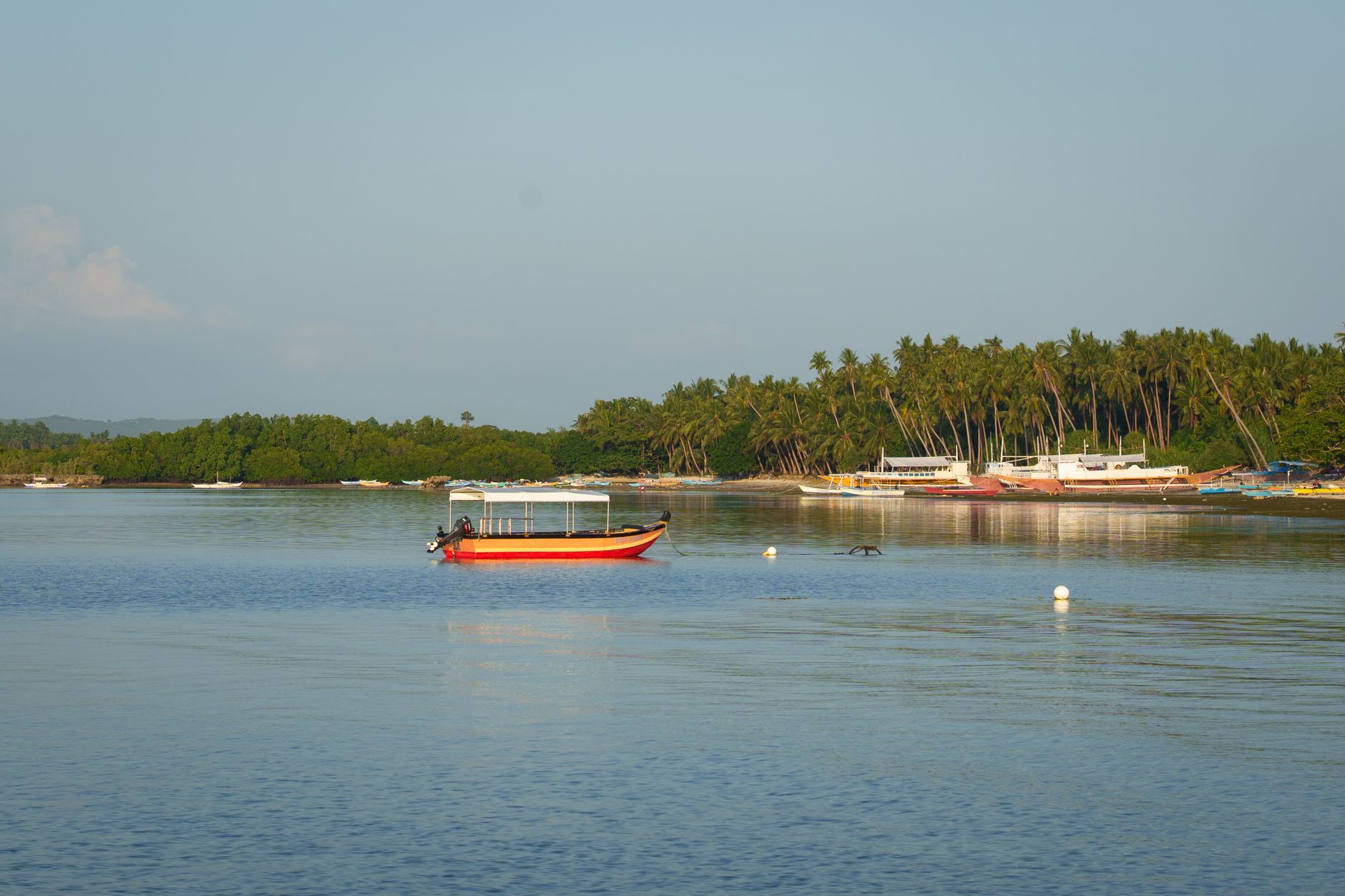 A small wooden boat resting on calm bay water at sunrise
