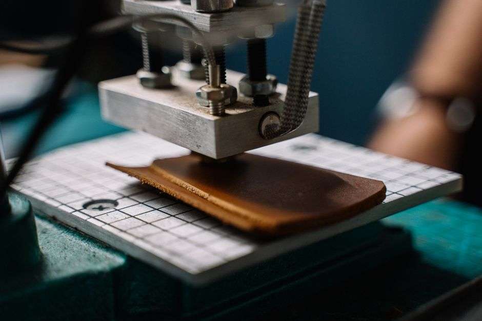 A craftsman cutting leather at a workshop bench