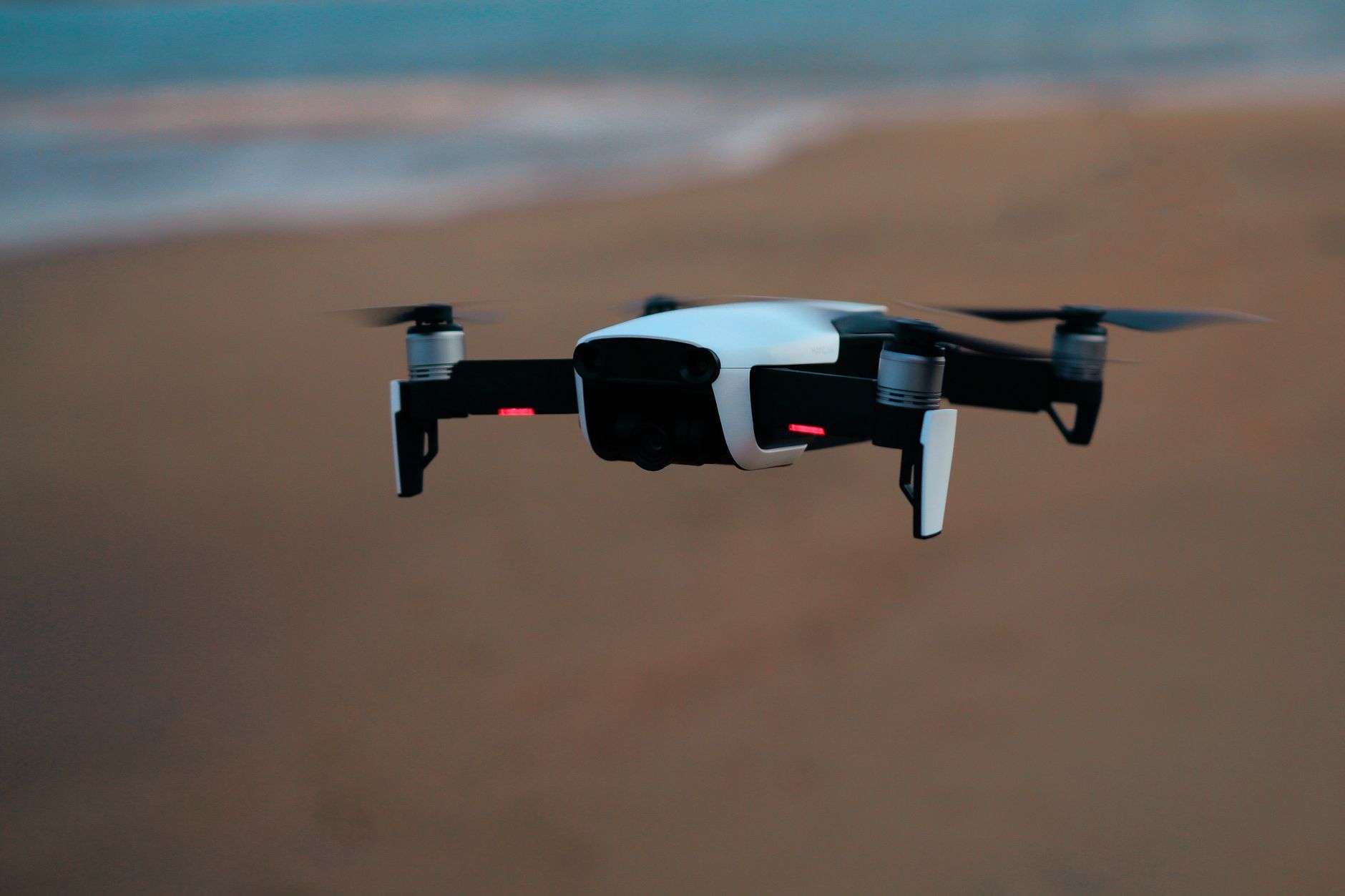 A small drone in flight over a beach and shoreline