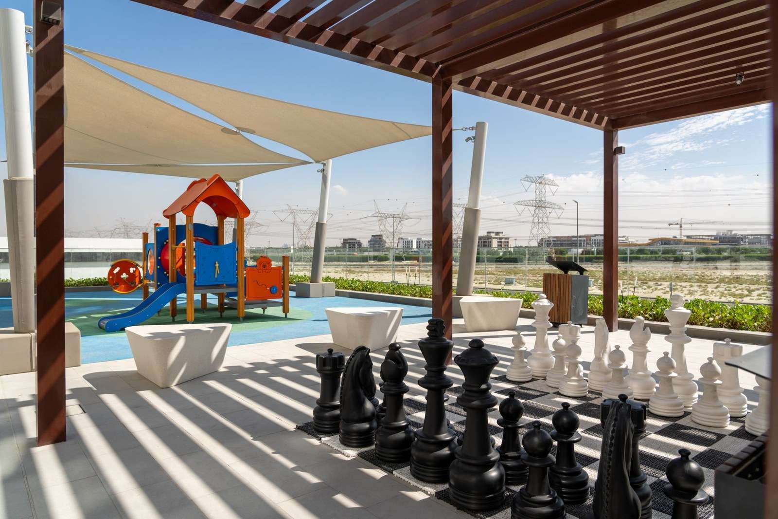 Colorful playground equipment in a public park with shade overhead