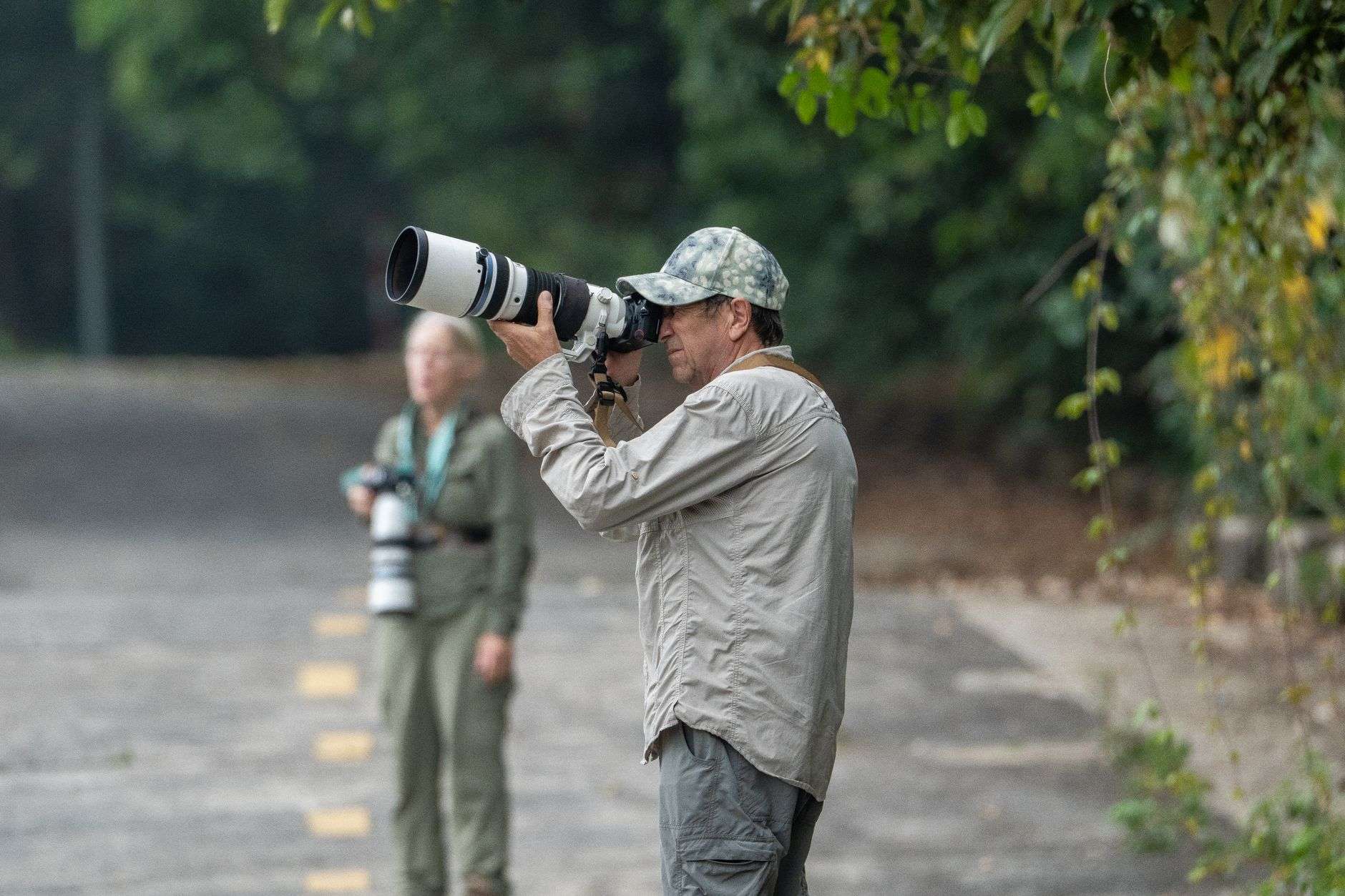 A nature photographer holding a camera in an outdoor setting