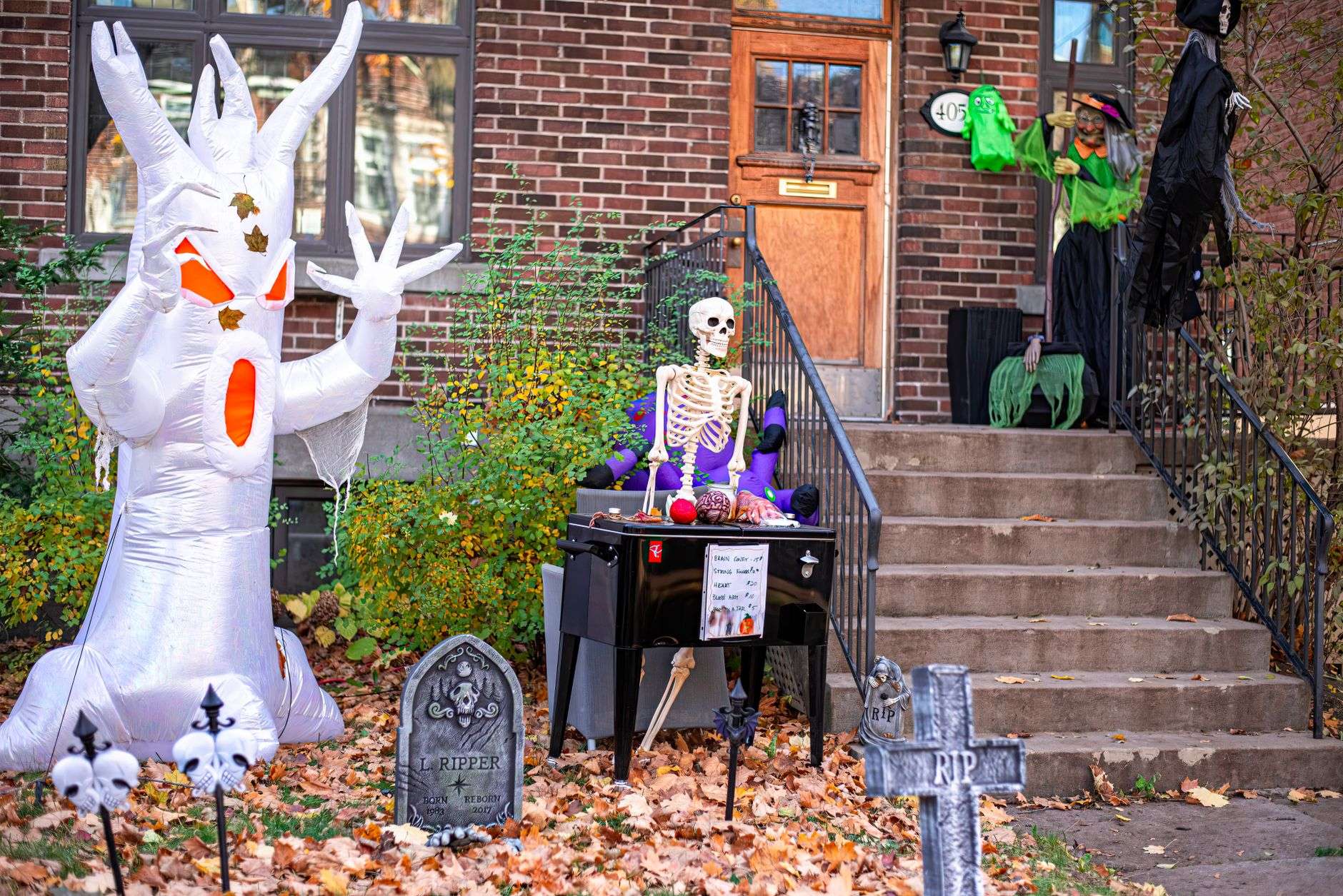 Spooky Halloween decorations featuring an inflatable ghost and skeleton on a porch.